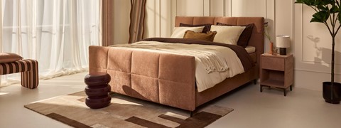 Een bed met een bruin bedframe