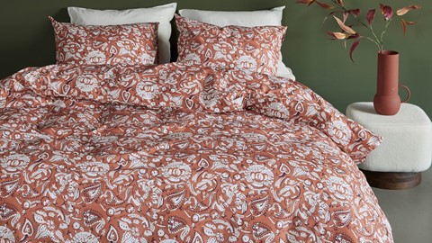 een bed met een dekbed met rood en wit patroon