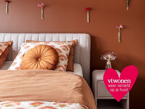 een bed met kussens en een lamp aan de muur