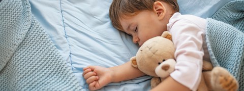 Een kind dat met een teddybeer slaapt