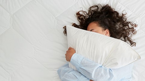 Een vrouw die in bed met een hoofdkussen ligt