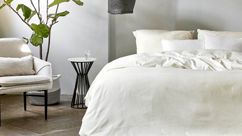 een bed met een witte deken en een zwarte lamp
