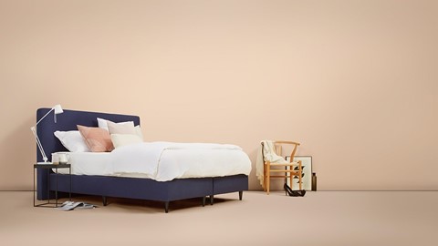 Een bed met kussens en een stoel in een kamer