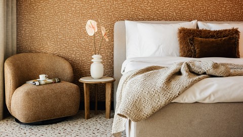 Een bed met een deken en een vaas met bloemen