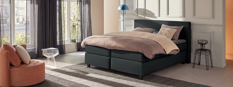 een bed met een roze deken en een blauwe lamp