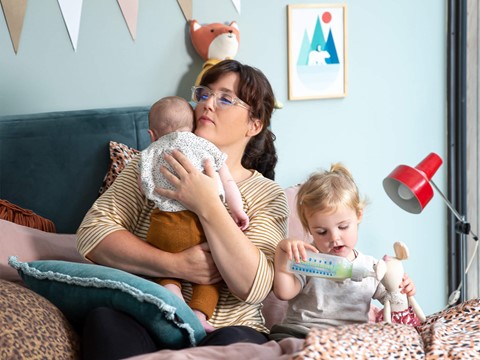 een vrouw die een baby vasthoudt en een baby die een fles voedt