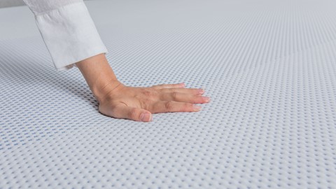 Hand duwt op koudschuim matras van Maxi
