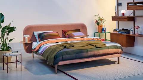 Een bed met kleurrijke dekens en kussens