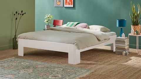 een bed met kussens en een stoel in een kamer