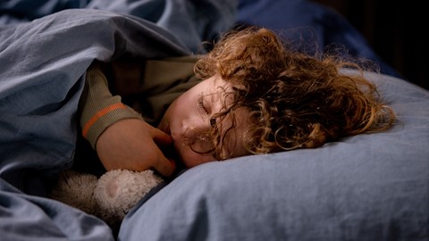 een kind dat in een bed slaapt met een knuffeldier