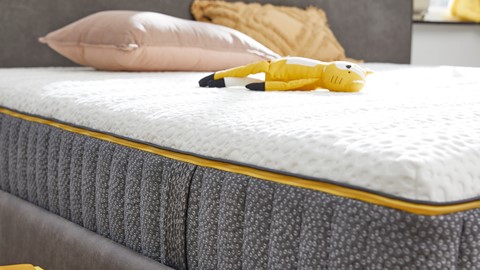 Een geel knuffeldier op een bed