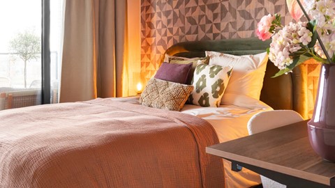 Een bed met kussens en een roze deken