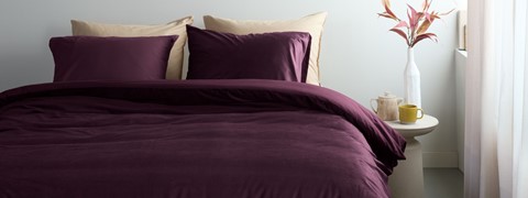 Een bed met paarse lakens en kussens