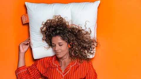 Een vrouw die op een kussen ligt met een koptelefoon op