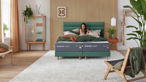 Een vrouw die op een bed zit