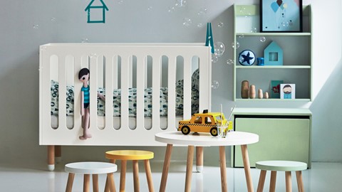 een babykamer met een wieg en tafel en speelgoed