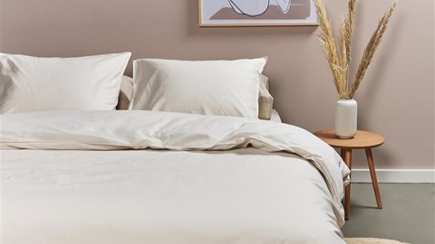 Een bed met witte lakens en kussens