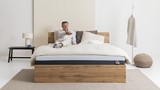 Een man zittend op een bed