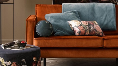 een bank met kussens en een ronde poef