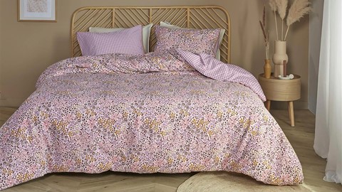 een bed met een roze dekbed en kussens