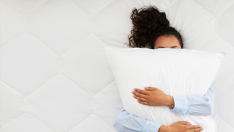 Een vrouw liggend op een bed met een kussen