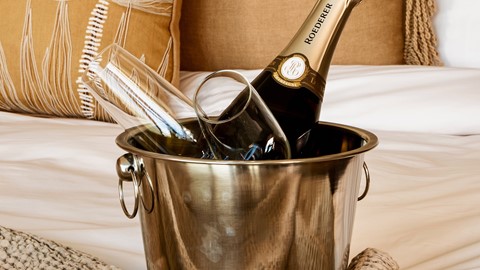 Een fles champagne in een bak wijnglazen