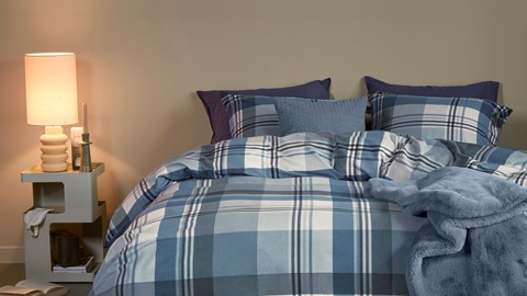 een bed met geruite beddengoed en een lamp