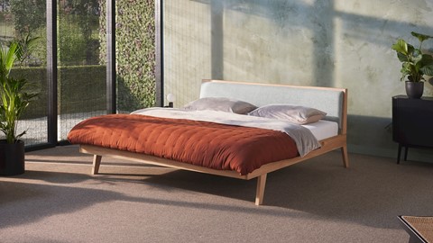 een bed met een rode deken en een lamp aan de zijkant