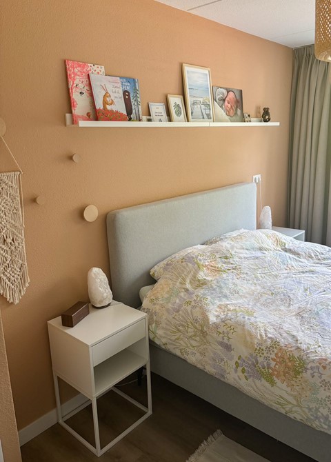 een bed met een deken en foto's aan de muur