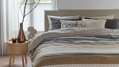 een bed met kussens en een plant ervoor
