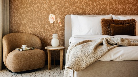 Een bed met kussens en een teddybeer in een vaas