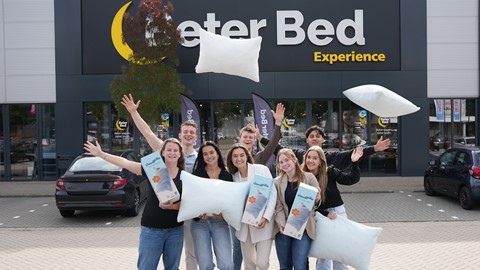 Een groep mensen die voor een foto met kussens stellen