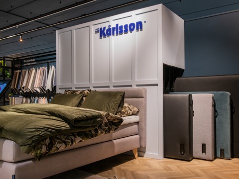 een bed met daarachter een witte muur