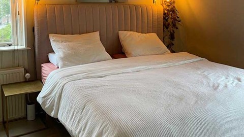 Slaapkamer van Marly van der Velden, beige bed met wit dekbedovertrek