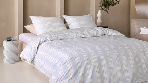 een bed met kussens en een plant