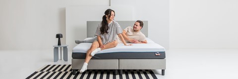 Een man en een vrouw die op een bed zitten