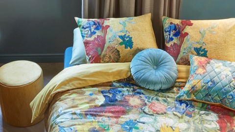 een bed met kleurrijke kussens en een blauw kussen erop