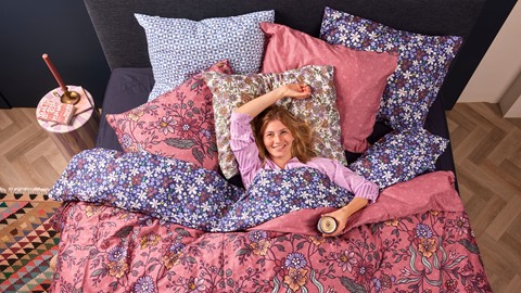 Een vrouw die in bed met een drankje ligt