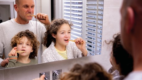 Een man en een meisje die hun tanden poetsen
