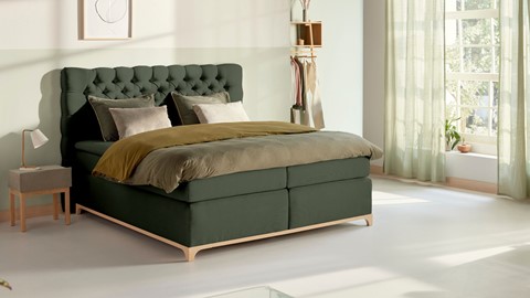 Kaki groene boxspring met massief houten frame in slaapkamer