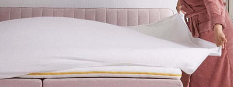 Een wit kussen op een roze bed