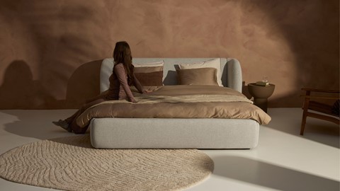 Een vrouw die op een bed zit